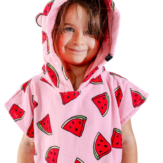 Enfant souriant avec poncho surf ALL-IN Watermelon capuche relevée, motif pastèques rose et rouge