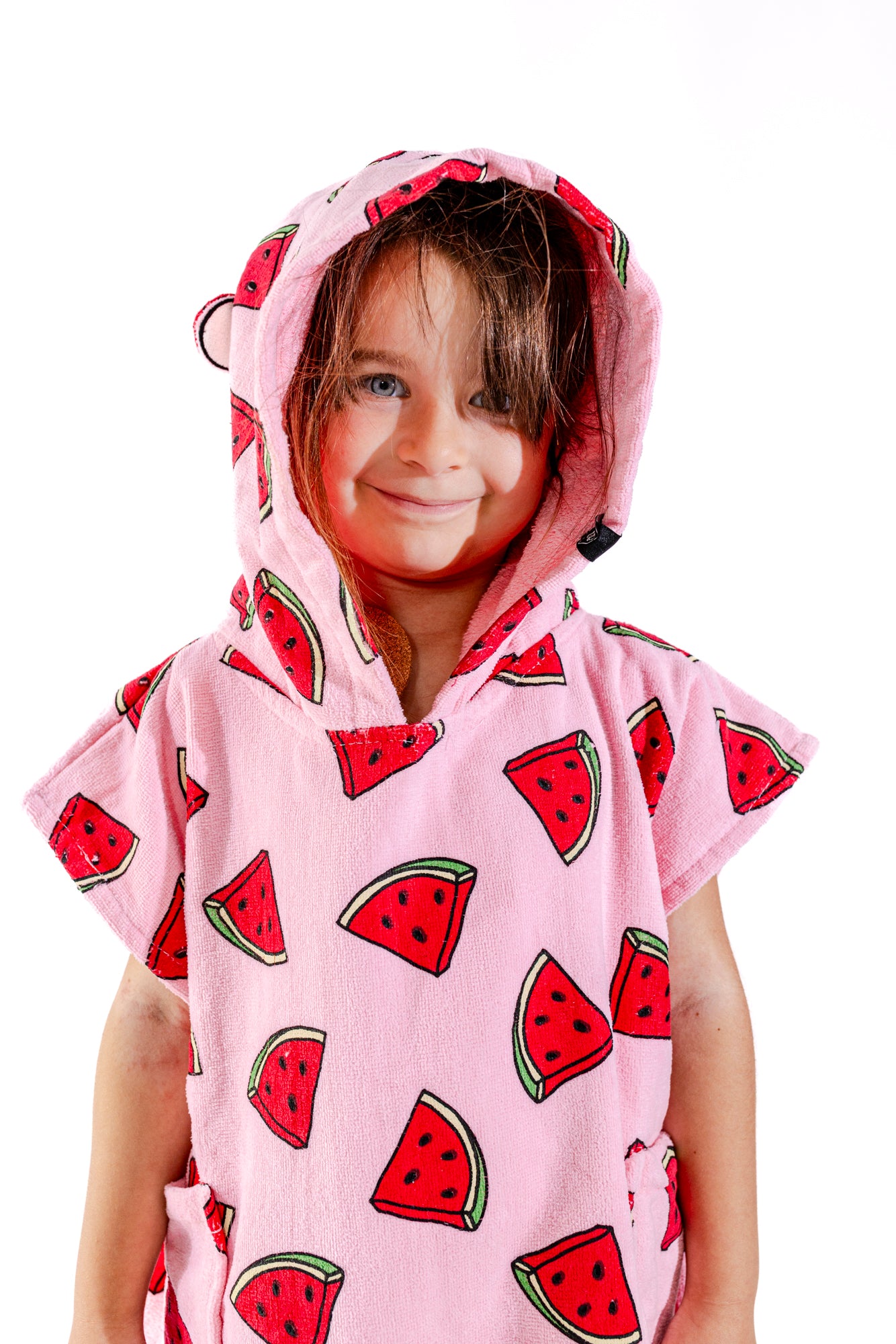 Enfant souriant avec poncho surf ALL-IN Watermelon capuche relevée, motif pastèques rose et rouge