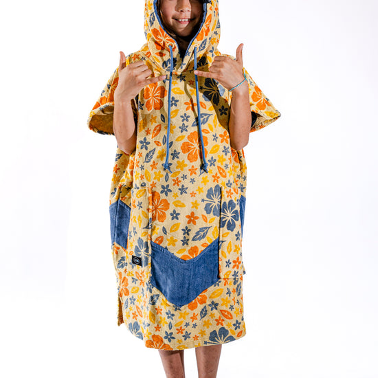 Poncho surf enfant ALL-IN Flore capuche relevée, motif floral jaune et orange, poches bleues, 6-9 ans