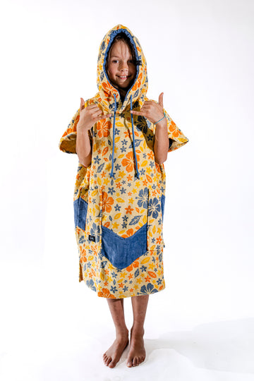 Poncho surf enfant ALL-IN Flore capuche relevée, motif floral jaune et orange, poches bleues, 6-9 ans