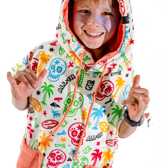 Poncho surf enfant ALL-IN Skully capuche relevée, motif têtes de mort colorées et palmiers, 6-9 ans