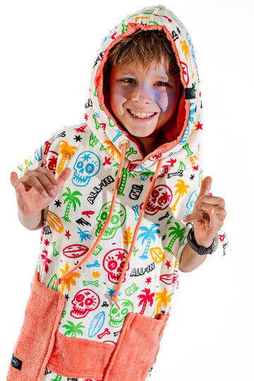 Poncho surf enfant ALL-IN Skully capuche relevée, motif têtes de mort colorées et palmiers, 6-9 ans