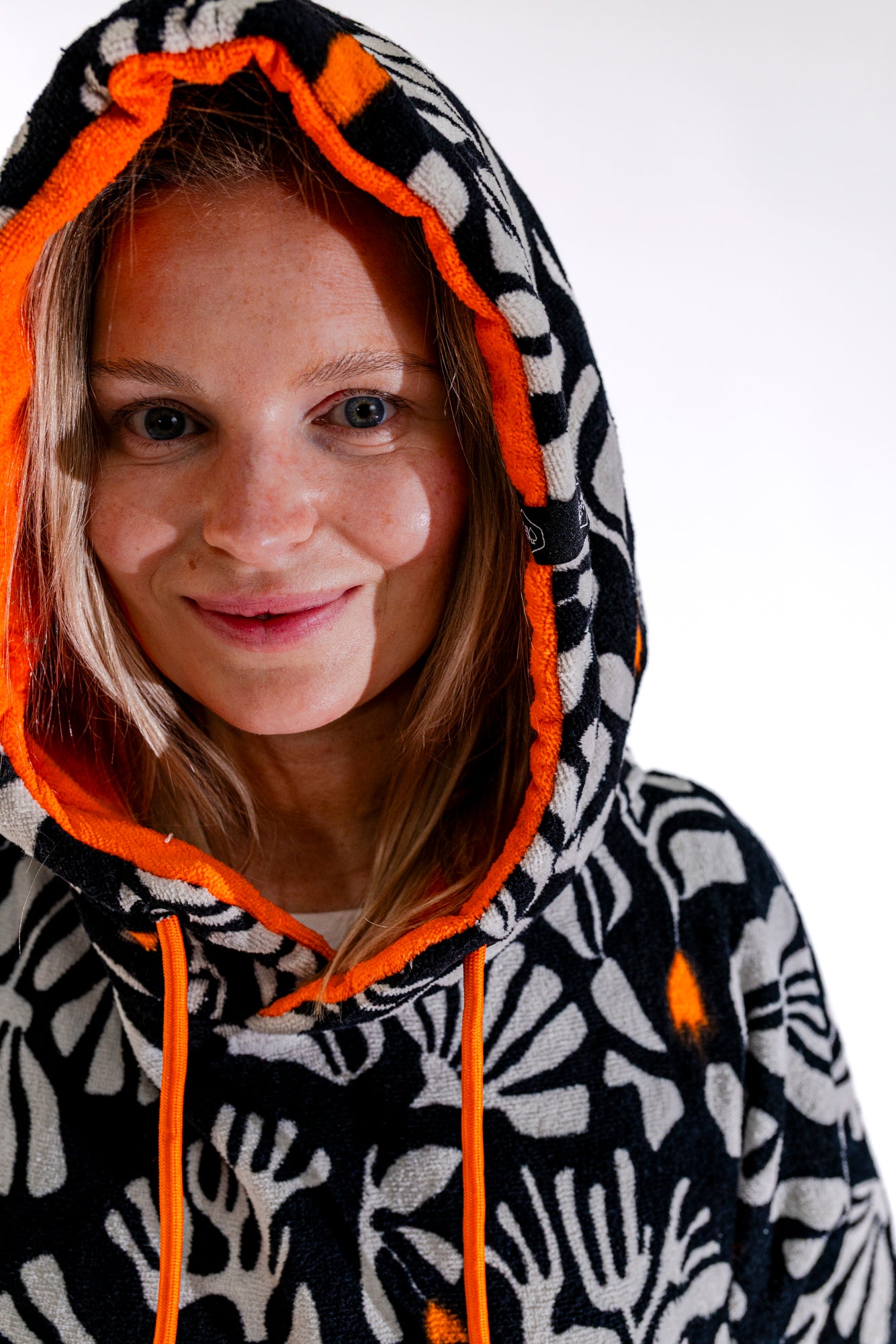 Détail capuche orange du poncho surf adulte ALL-IN Corail, motif floral noir et blanc contrasté