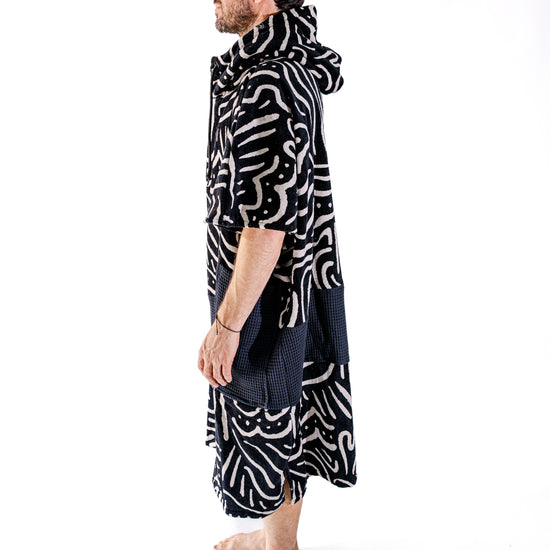 Poncho surf adulte ALL-IN Matis Black vue de profil, coupe ample V-Shape, poches noires, motif abstrait