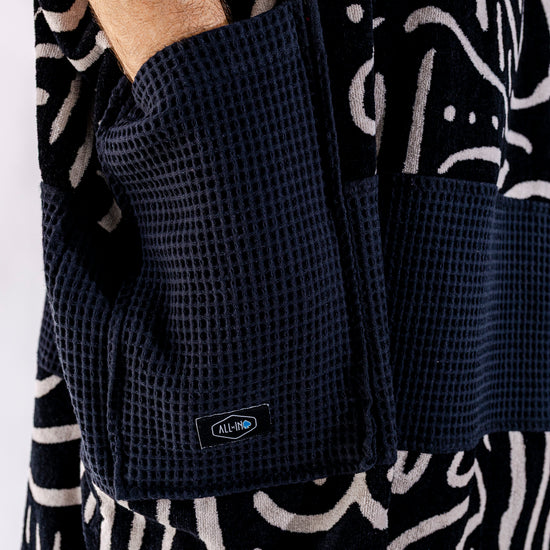 Détail poches noires du poncho surf adulte ALL-IN Matis Black, bande waffle noire contrastée