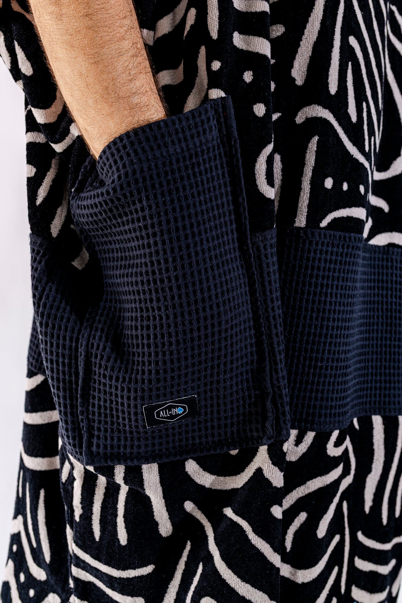 Détail poches noires du poncho surf adulte ALL-IN Matis Black, bande waffle noire contrastée