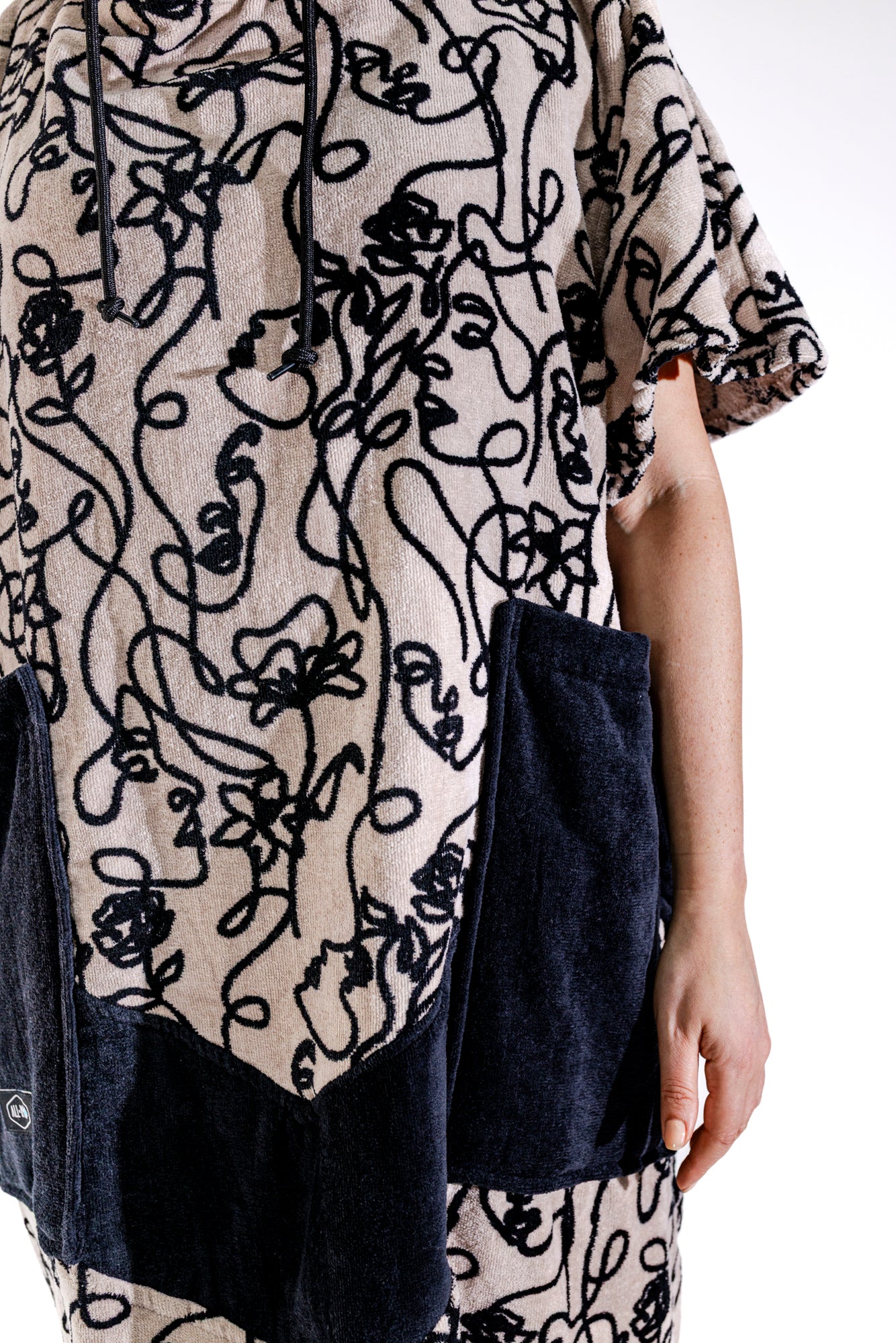 Détail poches noires et motif Oneline du poncho surf adulte ALL-IN, tissu 100% coton éponge