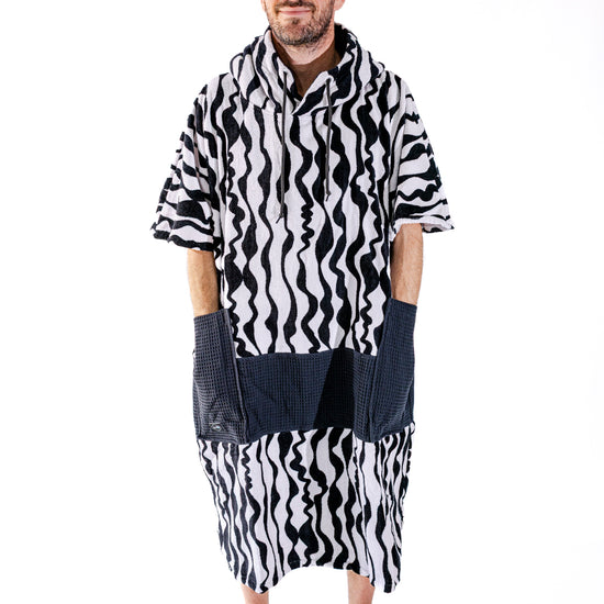 Poncho surf adulte ALL-IN Stripes vue de face, motif zébré noir et blanc, poches waffle noires