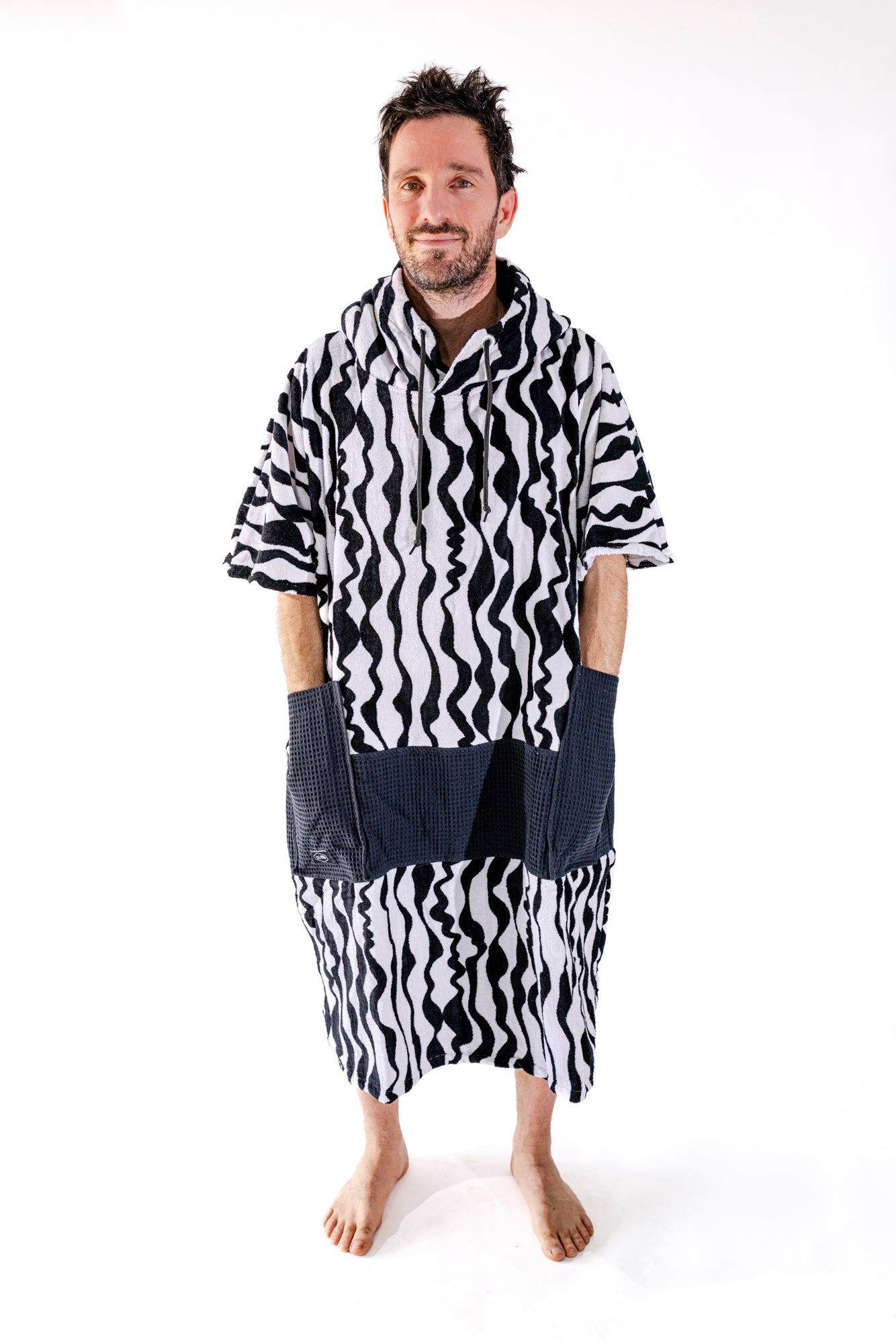 Poncho surf adulte ALL-IN Stripes vue de face, motif zébré noir et blanc, poches waffle noires