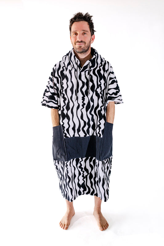 Poncho surf adulte ALL-IN Stripes vue de face, motif zébré noir et blanc, poches waffle noires