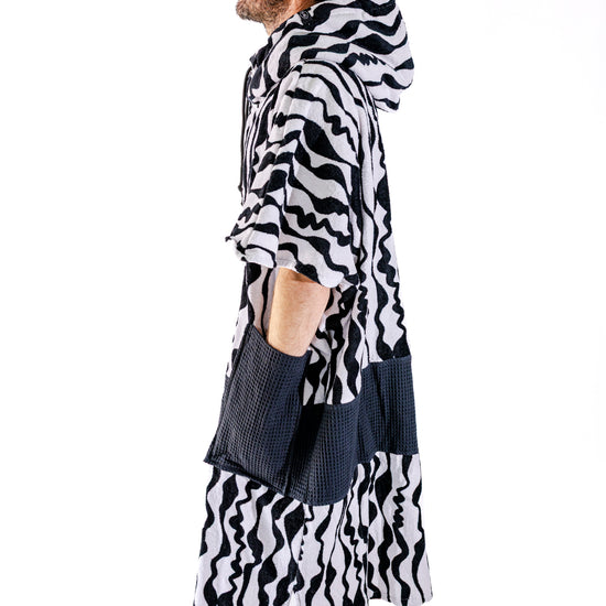 Poncho surf adulte ALL-IN Stripes vue de profil, coupe V-Shape, motif zébré noir et blanc, poches noires