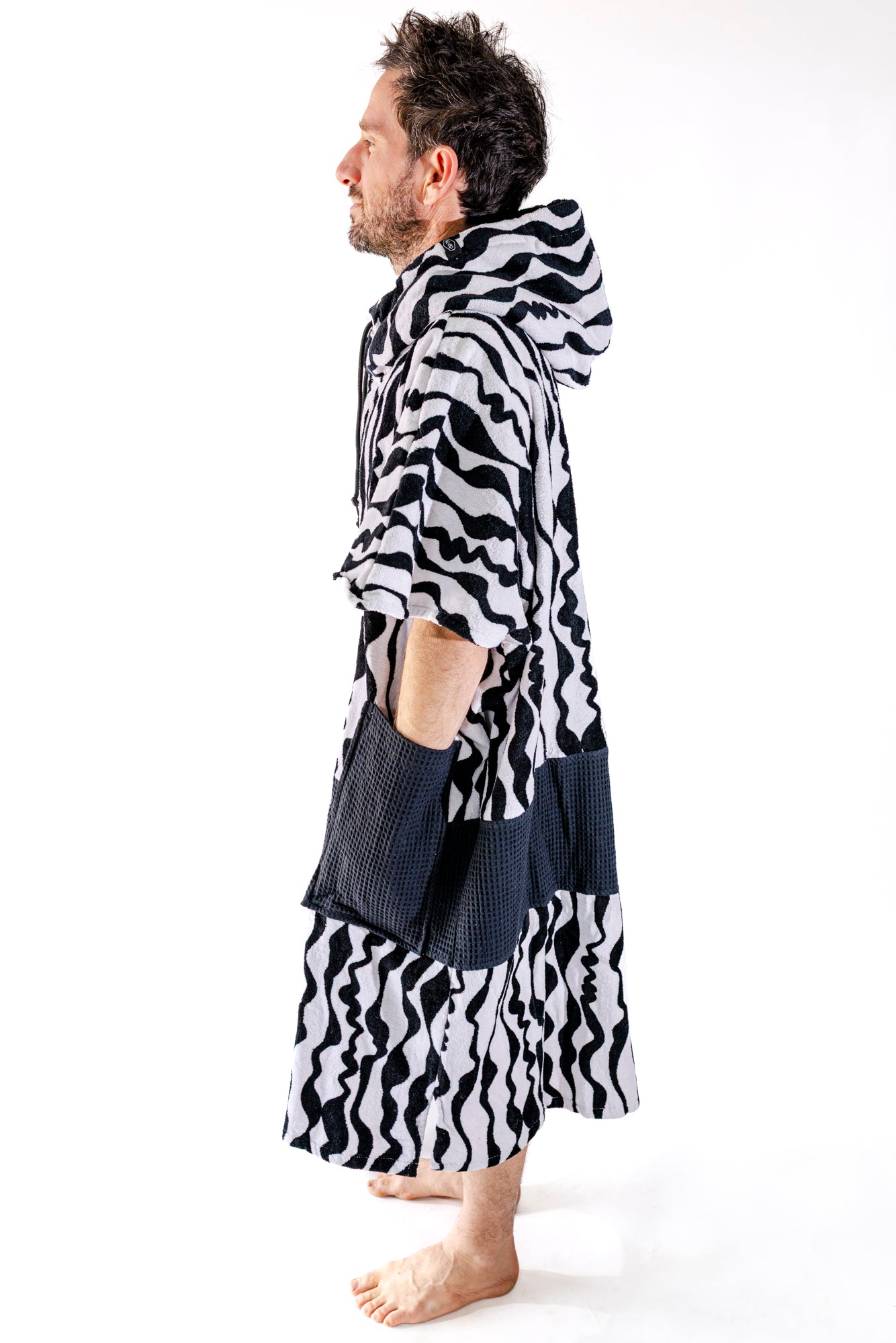 Poncho surf adulte ALL-IN Stripes vue de profil, coupe V-Shape, motif zébré noir et blanc, poches noires
