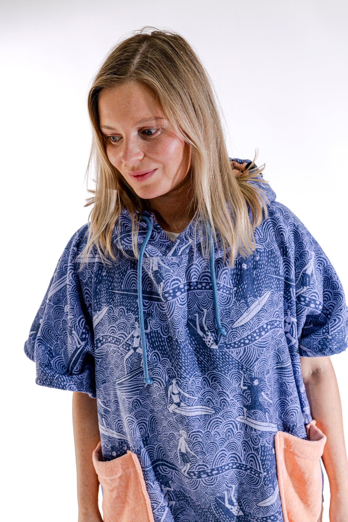 Poncho surf femme ALL-IN Surfing Madame vue trois quarts, motif vagues bleu, poche saumon visible