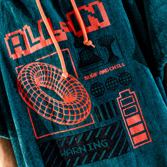 Détail imprimé rétro Y2K et logo ALL-IN brodé sur poncho surf adulte, coloris bleu pétrole