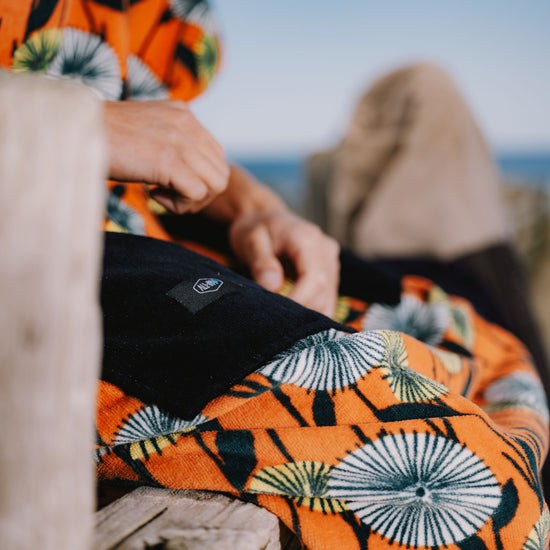 Détail des grandes poches latérales et du logo brodé ALL-IN sur un poncho de surf Dandelion en coton éponge épais et biologique