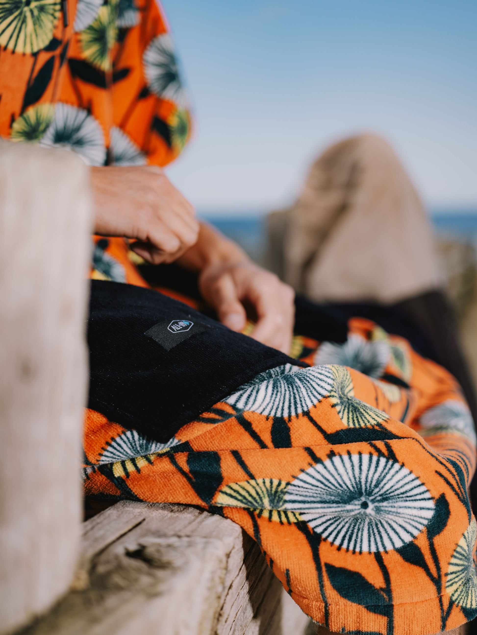 Détail des grandes poches latérales et du logo brodé ALL-IN sur un poncho de surf Dandelion en coton éponge épais et biologique