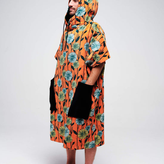 Vue de profil du poncho de surf ALL-IN Dandelion orange avec capuche ajustée et grandes poches noires