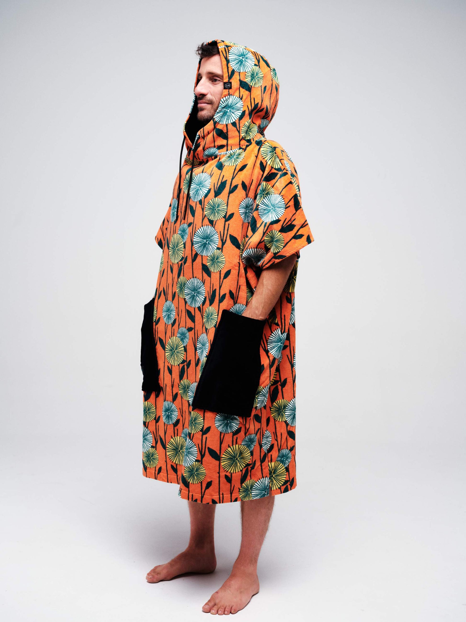 Vue de profil du poncho de surf ALL-IN Dandelion orange avec capuche ajustée et grandes poches noires