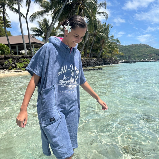 Poncho surf adulte ALL-IN Island porté en bord de mer tropical, coloris bleu indigo